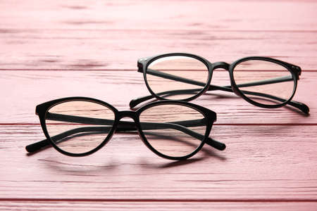 Different stylish eyeglasses on color wooden background, closeup
