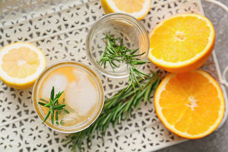 Tray with glass of tasty orange with rosemary on gray backgroundの写真素材