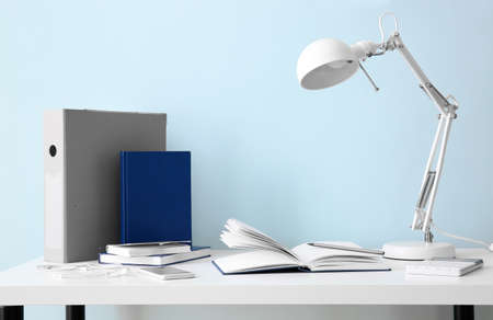 Modern workplace with notebooks and lamp near color wallの写真素材