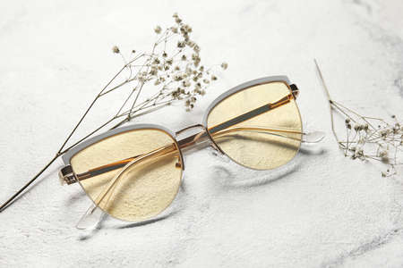 Stylish eyeglasses and flowers on light background, closeupの写真素材