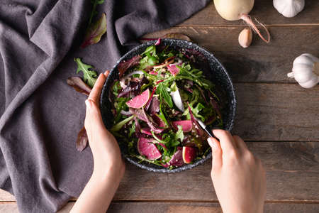 Woman eating tasty couscous with vegetables on wooden backgroundの写真素材