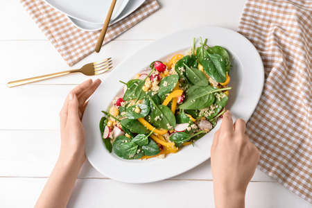 Woman eating tasty couscous with vegetables on light wooden backgroundの写真素材