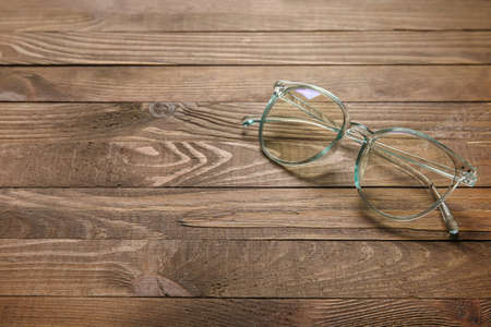 Stylish eyeglasses on wooden background