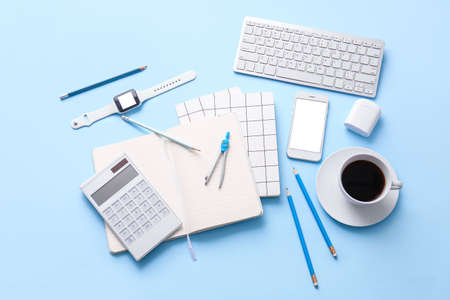 Different office tools, cup of coffee and devices on color tableの写真素材