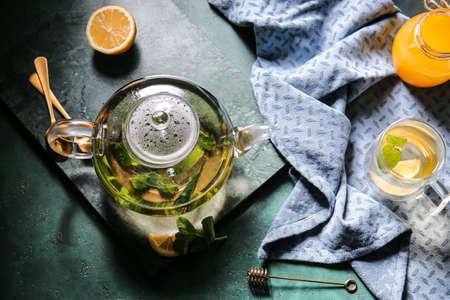 Pot with tasty green tea and ingredients on grunge backgroundの写真素材