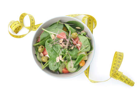 Plate with healthy salad and measuring tape on white background