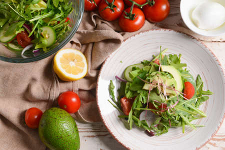 Plate with delicious salad on light wooden backgroundの写真素材