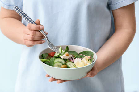 Woman eating healthy salad on light background, closeupの写真素材