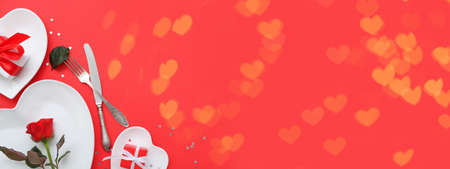 Stylish table setting and gifts for Valentine's Day on red background with space for textの写真素材