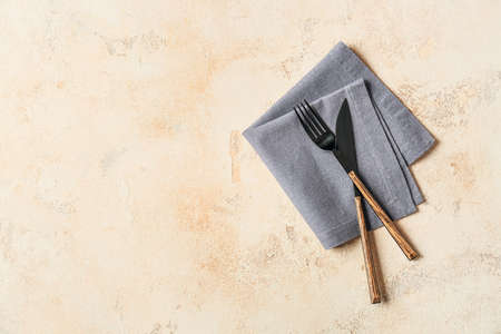 Stylish napkin and cutlery on light background