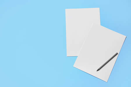 Blank sheets of paper and pencil on color background
