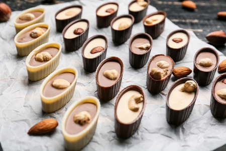 Tasty chocolate candies with nuts on baking parchment, closeupの写真素材