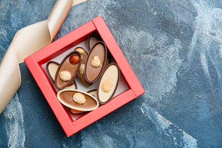 Box with tasty chocolate candies on color backgroundの写真素材