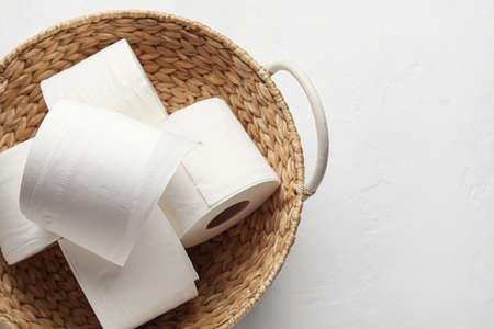 Wicker basket with rolls of toilet paper on white backgroundの写真素材