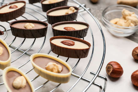 Tasty chocolate candies with nuts on grid, closeupの写真素材