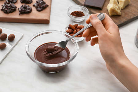 Woman preparing tasty chocolate candies on light background, closeupの写真素材