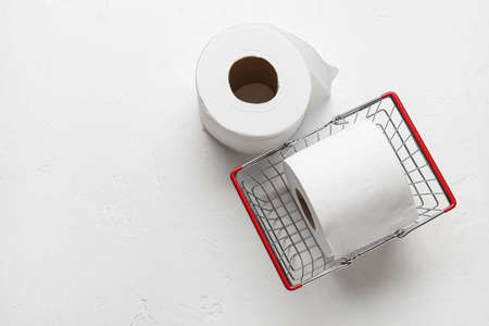 Shopping basket with rolls of toilet paper on white backgroundの写真素材