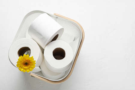Basket with rolls of toilet paper and flower on white backgroundの写真素材