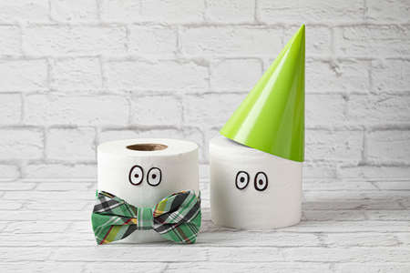 Creative composition with rolls of toilet paper and birthday hat near brick wall