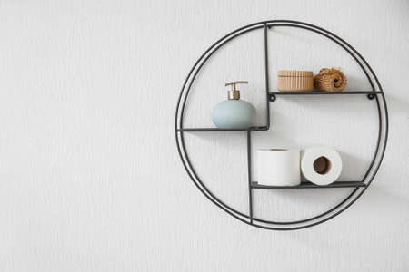 Shelf with rolls of toilet paper and bath supplies hanging on light wallの写真素材