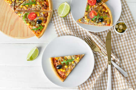 Plates with slices of tasty pizza on light wooden backgroundの写真素材