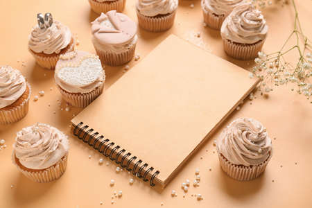 Tasty wedding cupcakes and recipe book on color backgroundの写真素材