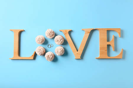Word LOVE with wedding rings and cupcakes on color backgroundの写真素材