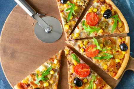 Board with slices of tasty pizza on color backgroundの写真素材