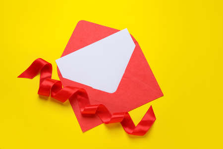 Envelope with blank card and ribbon on color background
