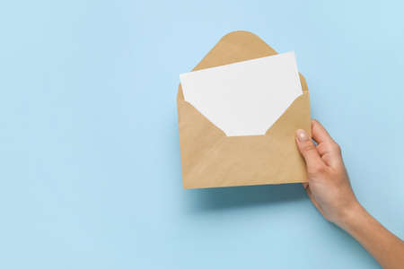 Female hand with envelope and blank card on color backgroundの写真素材