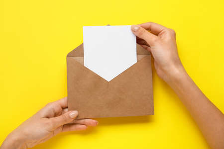 Female hands with envelope and blank card on color backgroundの写真素材