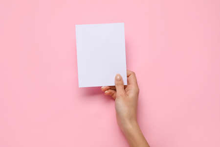 Female hand with blank card on color backgroundの写真素材