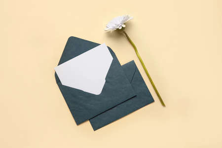 Envelopes with blank card and flower on color background
