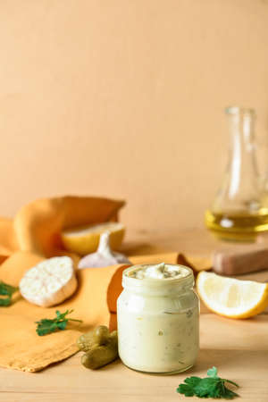 Glass jar with tasty tartare sauce and ingredients on color backgroundの写真素材