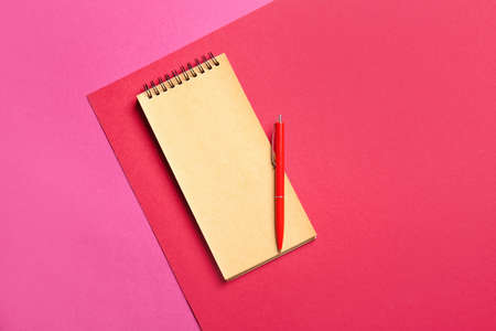 Blank notebook and red pen on color backgroundの写真素材