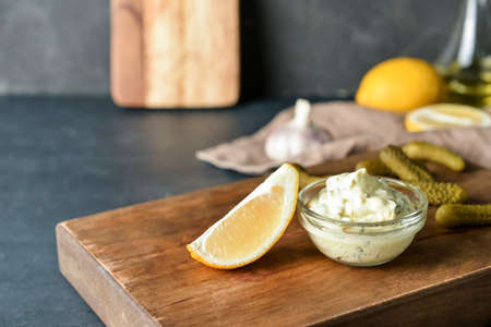 Bowl with tasty tartare sauce and lemon on dark background, closeupの写真素材
