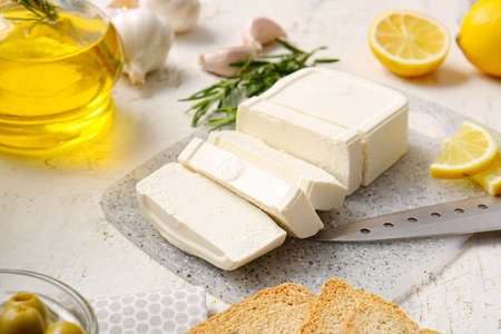 Board with cut feta cheese on light tableの写真素材