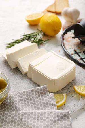 Board with cut feta cheese on light tableの写真素材