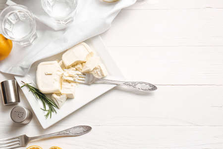 Plate with crushed feta cheese and rosemary on light wooden backgroundの写真素材