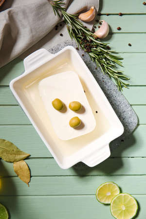 Baking dish with feta cheese and olives on color wooden backgroundの写真素材