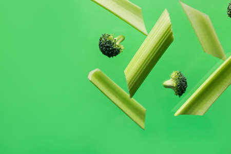Flying celery and broccoli on color backgroundの写真素材