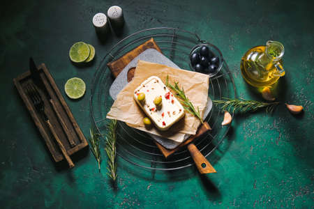Board with feta cheese, spices and olives on color backgroundの写真素材