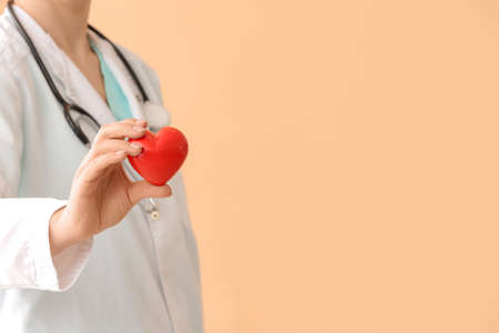 Female cardiologist with red heart on color backgroundの写真素材