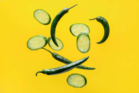 Flying cucumber slices and chili peppers backgroundの写真素材