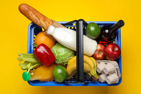 Shopping basket with food on color backgroundの写真素材