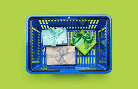 Shopping basket with gift boxes on color backgroundの写真素材