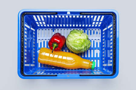 Shopping basket with juice and vegetables on light backgroundの写真素材