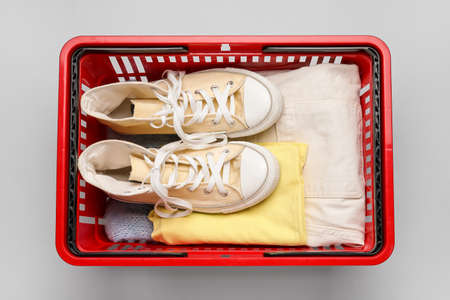 Shopping basket with shoes and clothes on light backgroundの写真素材