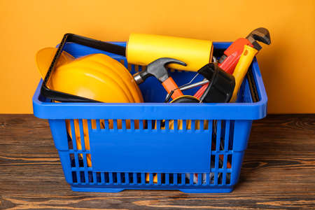 Shopping basket with builder's supplies on table near color wallの写真素材
