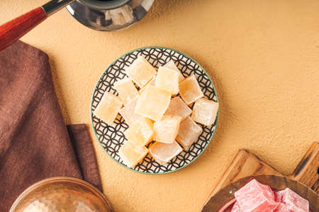 Plate with Turkish delight on color background